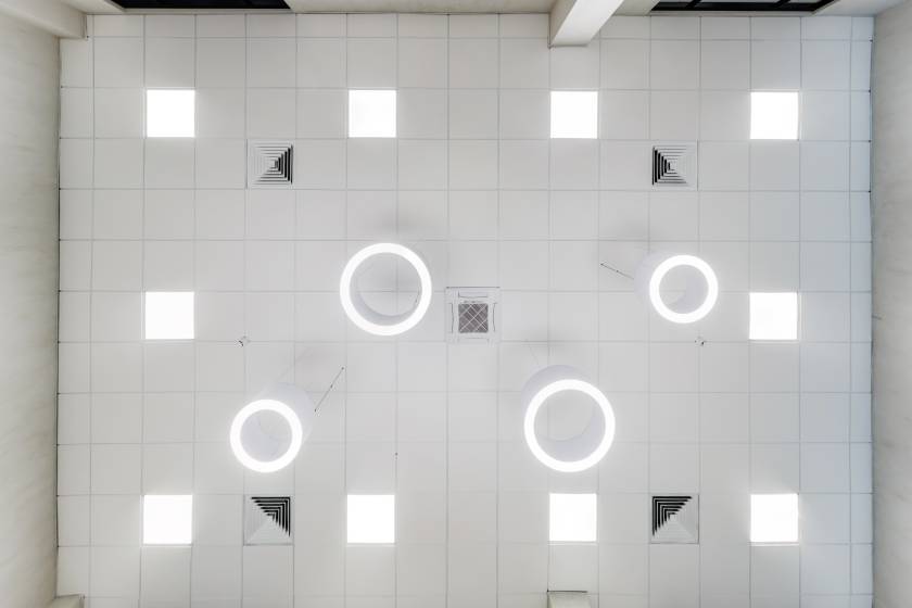 cassette suspended ceiling with square and round halogen spots lamps and drywall construction in empty room in apartment or house. Stretch ceiling white and complex shape. Looking up view