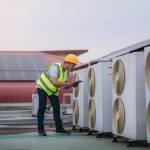 Engineers is checking the air conditioning cooling system of a major building or industrial facility. Background is solar cell on the roof.